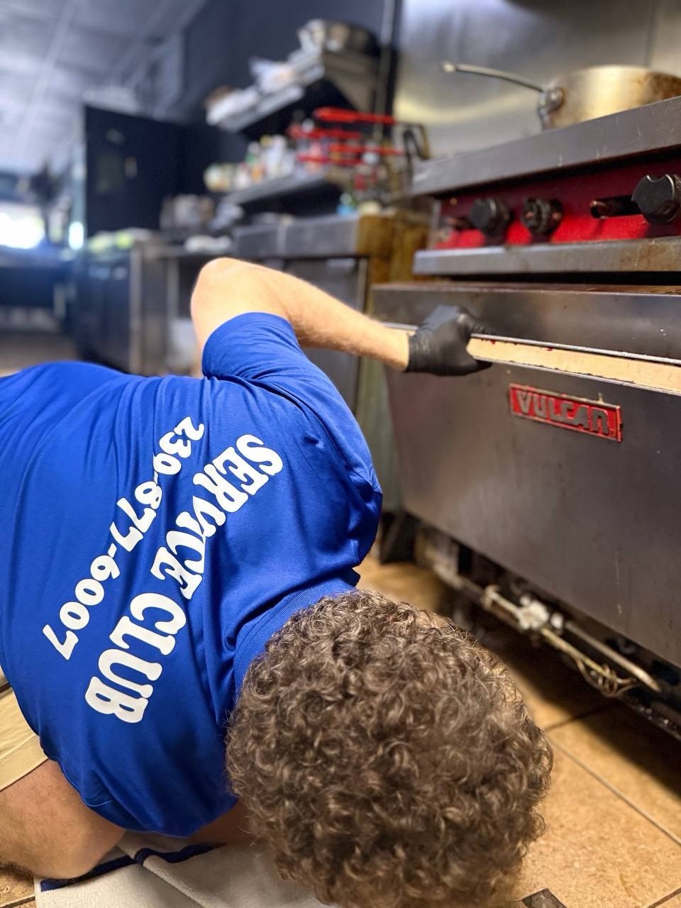 Technician servicing a commercial gas griddle in a Naples restaurant kitchen