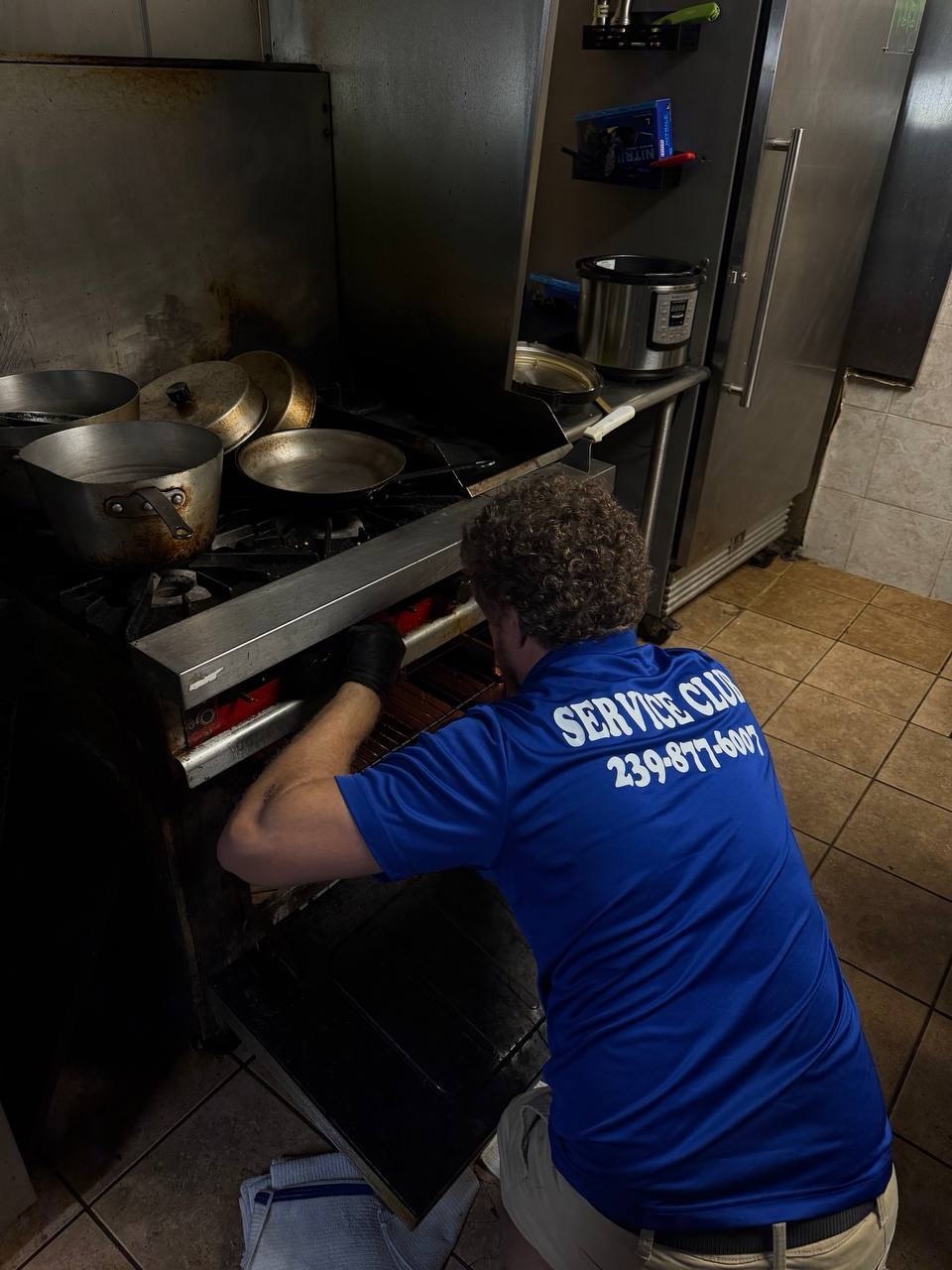 Technician repairing a commercial cooking appliance in a restaurant kitchen