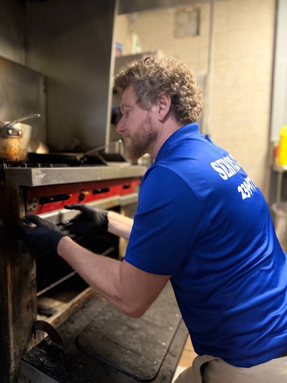 Technician replacing a part on a commercial cooking appliance during service